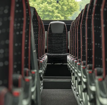 File di sedili con poggiatesta grigi e tende rosse nel pullman Comfort
