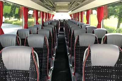 Rows of seats in a Comfort coach with red curtains
