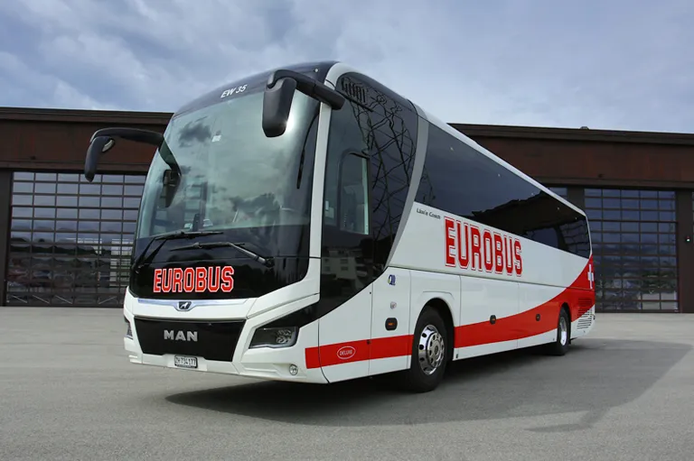 A EUROBUS Deluxe coach parked in front of a hall