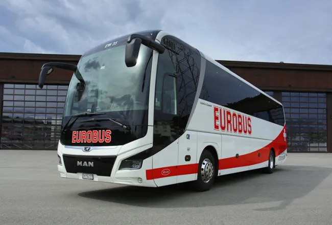 A EUROBUS Deluxe coach parked in front of a hall