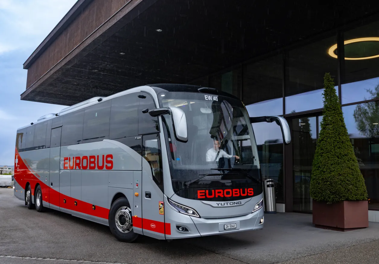 Un car EUROBUS s’arrête devant l’entrée d’un bâtiment à façade vitrée