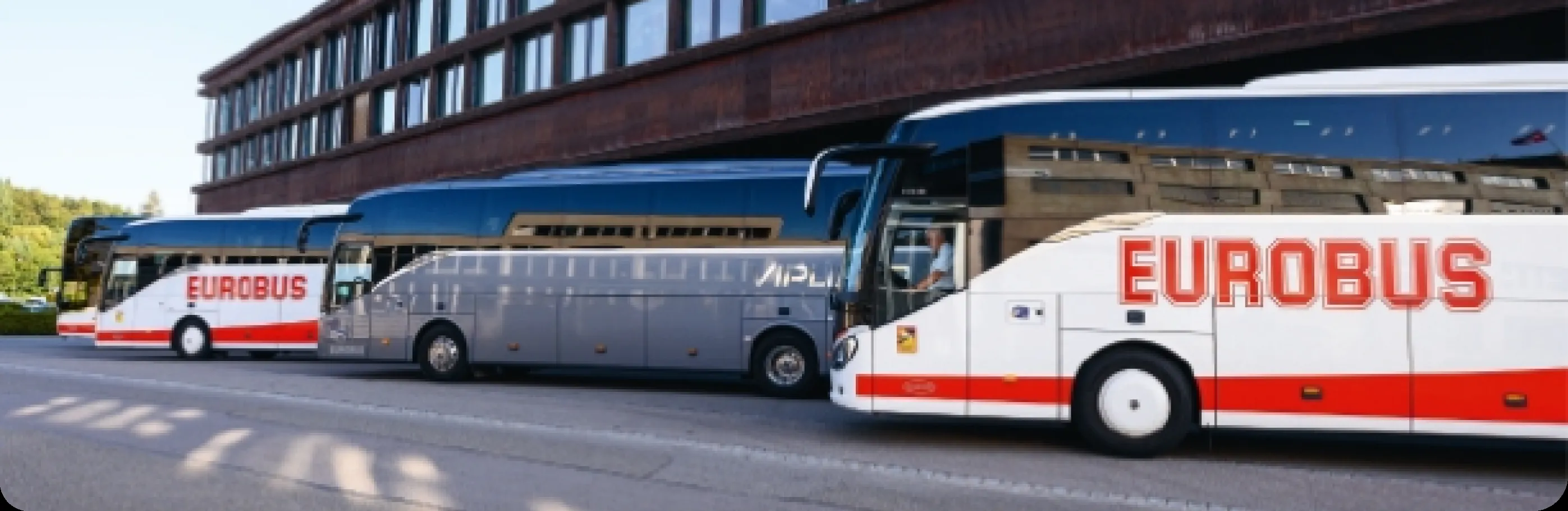 Three EUROBUS coaches parked one behind the other in front of a building