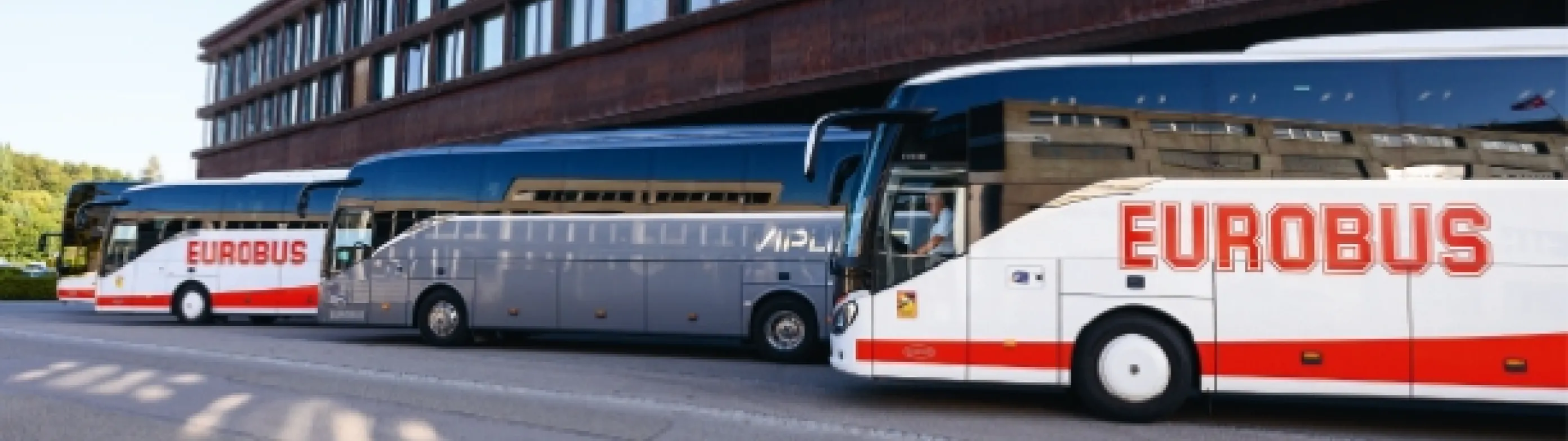Three EUROBUS coaches parked one behind the other in front of a building