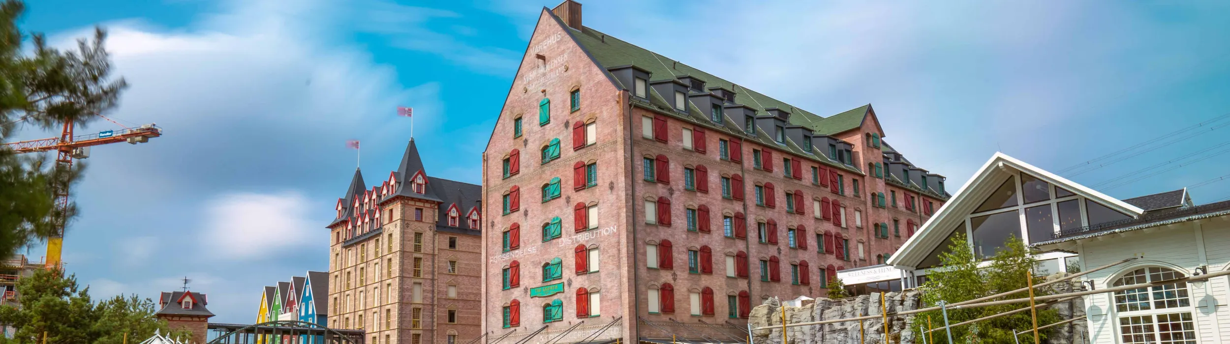 L’edificio in mattoni dell’Hotel Krønasår con tetto verde e persiane rosse e verdi, a sinistra una torre con tetti a punta e casette di legno colorate