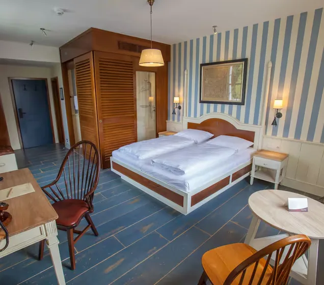 Una camera d’hotel con letto matrimoniale, carta da parati a righe blu e mobili in legno