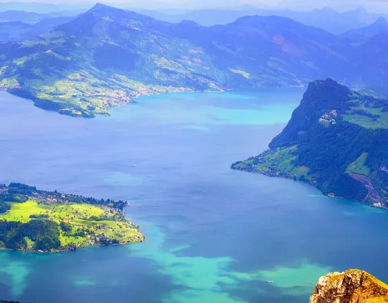 View from above of a branching lake between green hills and mountains
